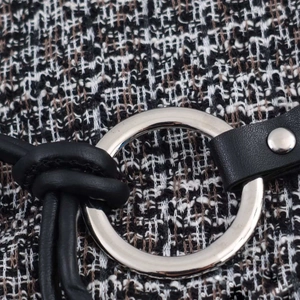 Detailed macro shot of tweed fabric texture with a polished silver metal ring buckle