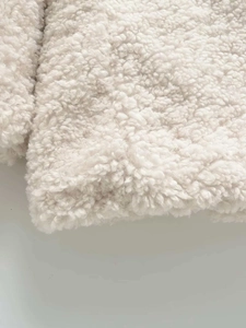 Détail en gros plan de la texture douce en sherpa blanc crème sur la veste
