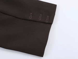 Dettaglio della manica di un blazer scuro con tre asole decorative verticali cucite