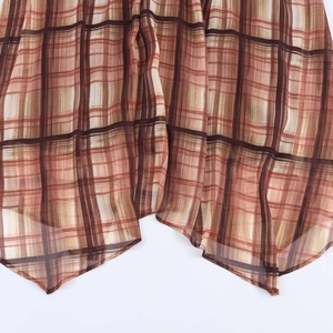 Detail of sheer brown plaid chiffon dress featuring a stylish asymmetrical handkerchief hemline