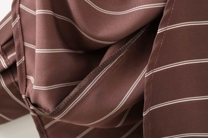 Dettaglio del tessuto della camicia a righe marroni con cuciture precise e tagliacuci