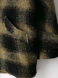 Detailed view of the green and black plaid wool texture and functional pocket seam