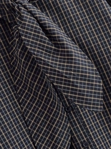 Détail d'une chemise à carreaux foncée avec col à nœud papillon et texture de tissu