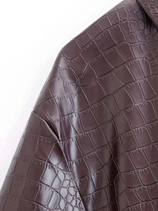 Détail du tissu en similicuir marron foncé avec gaufrage crocodile et coutures précises