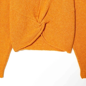 Orange rib-knit sweater with a stylish twist knot hem detail on white background