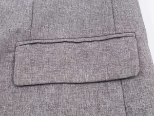Macro detail of herringbone blazer fabric with pocket flap and gray textile texture