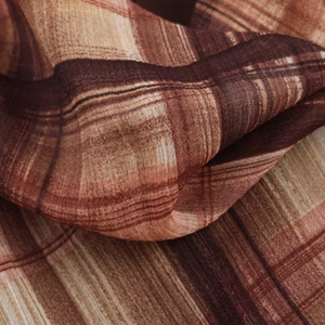 Macro detail of the woven plaid fabric texture in warm brown and beige tones