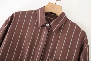 Dettaglio camicia marrone a righe con taschino sul petto e colletto a rever classico