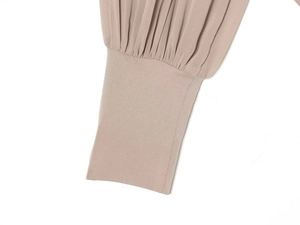 Detailed close-up of ribbed cuffs and pleated chiffon fabric on a nude high-neck bodysuit