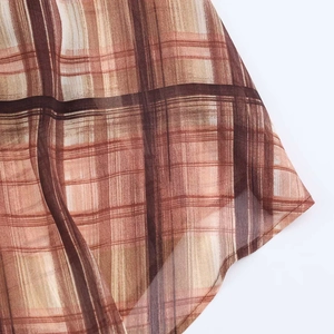 Detail of sheer brown plaid dress fabric showing exquisite rolled hem and airy texture