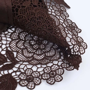 Close-up of brown floral lace fabric with intricate hollow embroidery on a camisole top