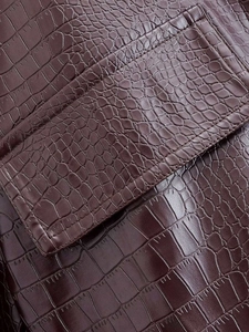 Vue macro détaillée de la texture en cuir gaufré crocodile marron foncé sur la veste