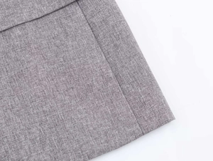 Close-up of grey herringbone fabric texture and fine stitching on the blazer suit