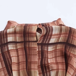 Detail view of high neckline with teardrop cutout on brown plaid dress fabric