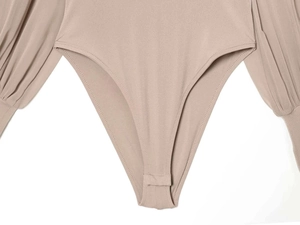 Detail of the snap button closure and cuff of a taupe high-neck knit long sleeve bodysuit