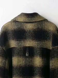 Detail of olive green and black checkered wool coat showing back locker loop feature