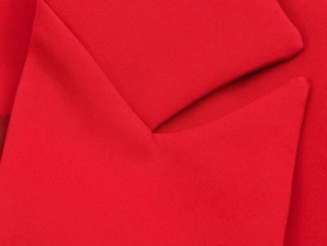 Macro shot of bright red woven fabric texture and stitching detail for a stylish blazer