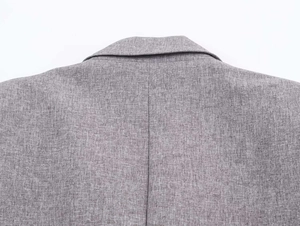 Close-up of the grey herringbone blazer showing detailed shoulder and neck stitching