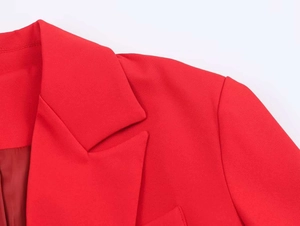 Detail of red blazer showing peak lapels, shoulder seams and smooth fabric texture