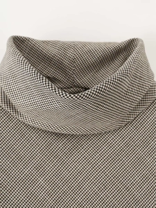 Detailed macro view of the houndstooth pattern and high neckline of this elegant knit top