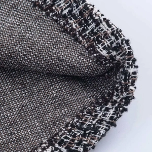 Macro detail of the woven tweed fabric showing grey and black textured pattern and hem
