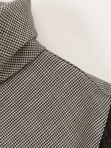 Detailed view of houndstooth sleeveless top featuring high neck and black lace patchwork