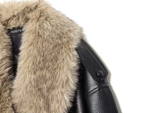 Détail du col amovible en fausse fourrure marron clair sur la veste en similicuir noir