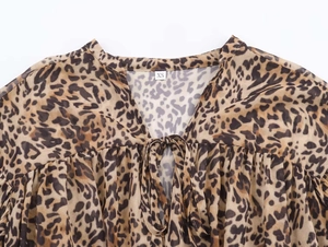 Detailed close-up of V-neckline with leopard print fabric and size XS label on a dress