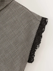 Macro view of houndstooth fabric with black lace edge detail on high neck sleeveless top
