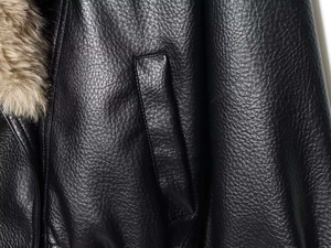 Détail macro du cuir noir texturé et du col en fausse fourrure marron épais