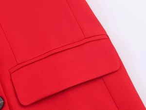 Detail of red blazer fabric showing double-breasted stitching and pocket flap design