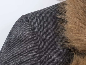 Close-up of dark grey textured fabric with premium brown faux fur collar detail