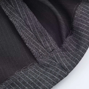 Dettaglio della trama del tessuto gessato e della cucitura professionale overlock di qualità