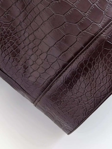 Gros plan détaillé de la texture crocodile marron foncé sur une veste en similicuir
