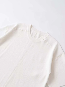Gros plan sur un pull en maille blanche à col rond avec couture centrale et détails