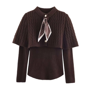 Dettaglio del set due pezzi in maglia marrone con poncho a trecce e sciarpa di seta a fiori
