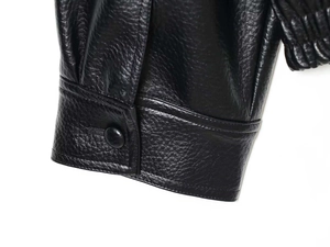Gros plan du poignet d'une veste en similicuir noir avec grain de cuir et bouton classique