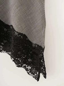 Detail of houndstooth pattern fabric with elegant black lace trim on the hem