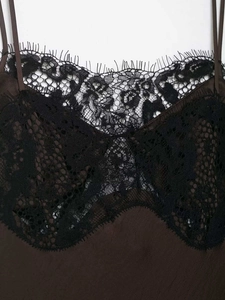 Détail de la dentelle noire raffinée sur le corsage d'une robe en satin marron