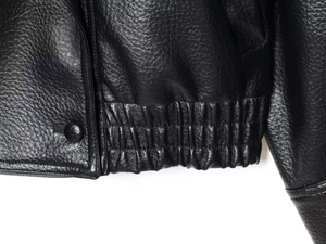 Détail d'une veste en simili cuir noir avec ourlet élastique et bouton pression mat