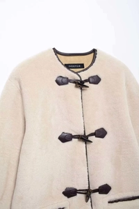 Primer plano detallado de chaqueta de piel crema con bordes de cuero y botones de palanca