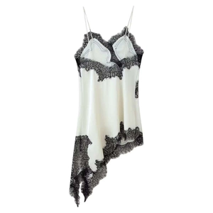 Close-up of white satin dress featuring black eyelash lace trim and asymmetric hem detail