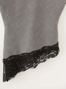 Detail of houndstooth fabric with intricate black floral lace patchwork and irregular hem