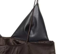 Détail rapproché du patchwork en similicuir noir et satin marron sur un haut caraco