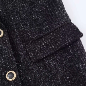 Detail of black tweed jacket featuring metallic silver threads and gold-rimmed buttons