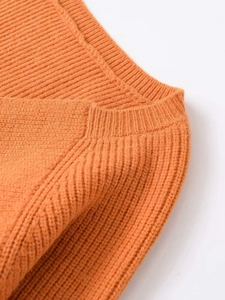 Detailed macro view of vibrant orange ribbed knit texture and shoulder seam craftsmanship