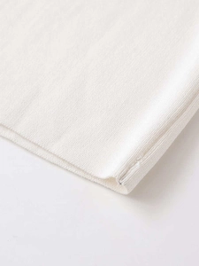 Vue détaillée de la texture du tricot blanc et de la couture fine de l'ourlet du vêtement