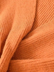 Macro texture of caramel ribbed knit fabric showing soft fiber and ribbed weave detail