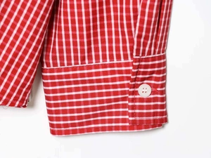 Detail of red and white gingham shirt cuff with a white four-hole button and stitching