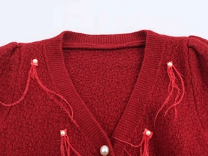 Detailed view of red V-neck knit sweater with pearl beads and feather textures